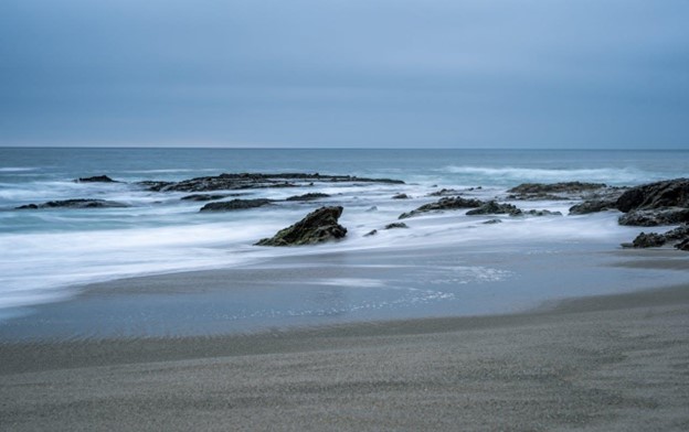 A photo of waves and rocks taken from the beach