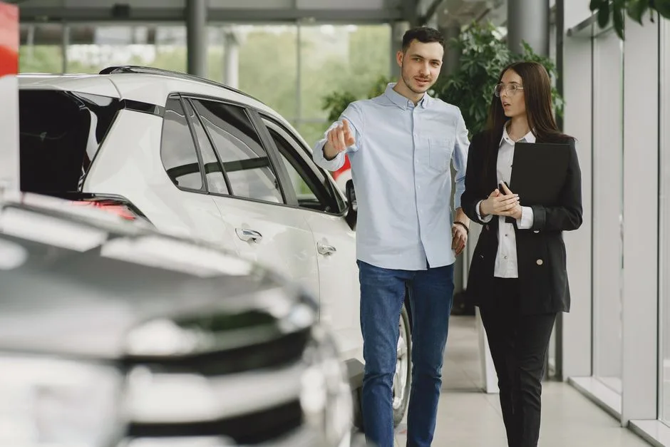 Family reviewing paperwork with car salesman at Oklahoma dealership showroom with vehicles in background