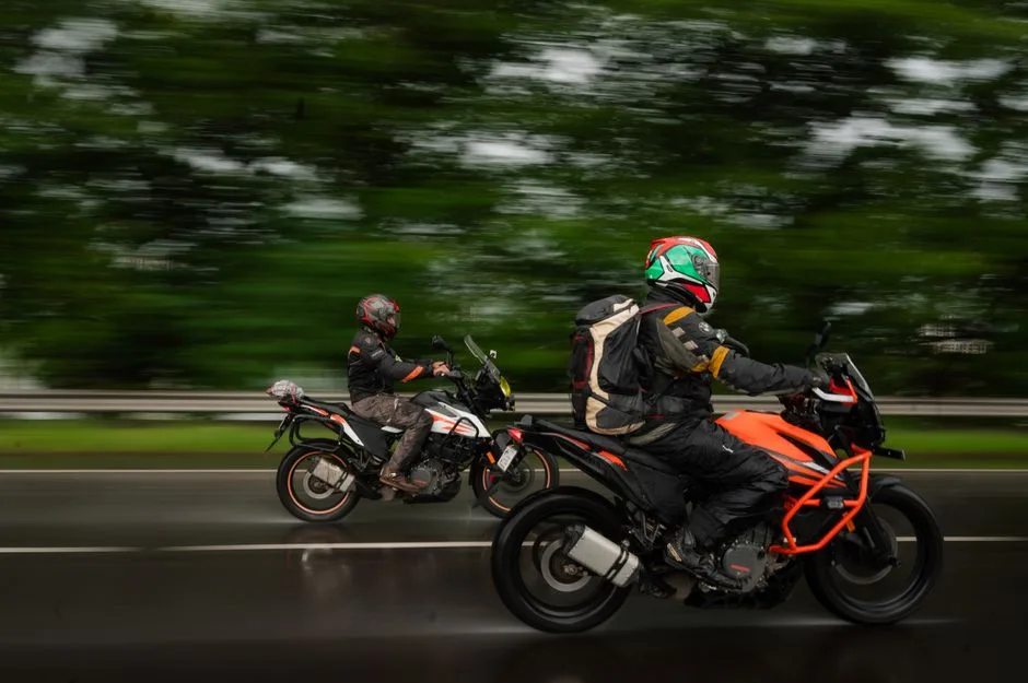 KTM motorcycle rider in full safety gear including helmet, jacket and gloves standing next to orange KTM bike