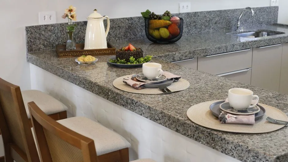 Quartz and granite countertop samples displayed side by side in a modern kitchen showroom for comparison